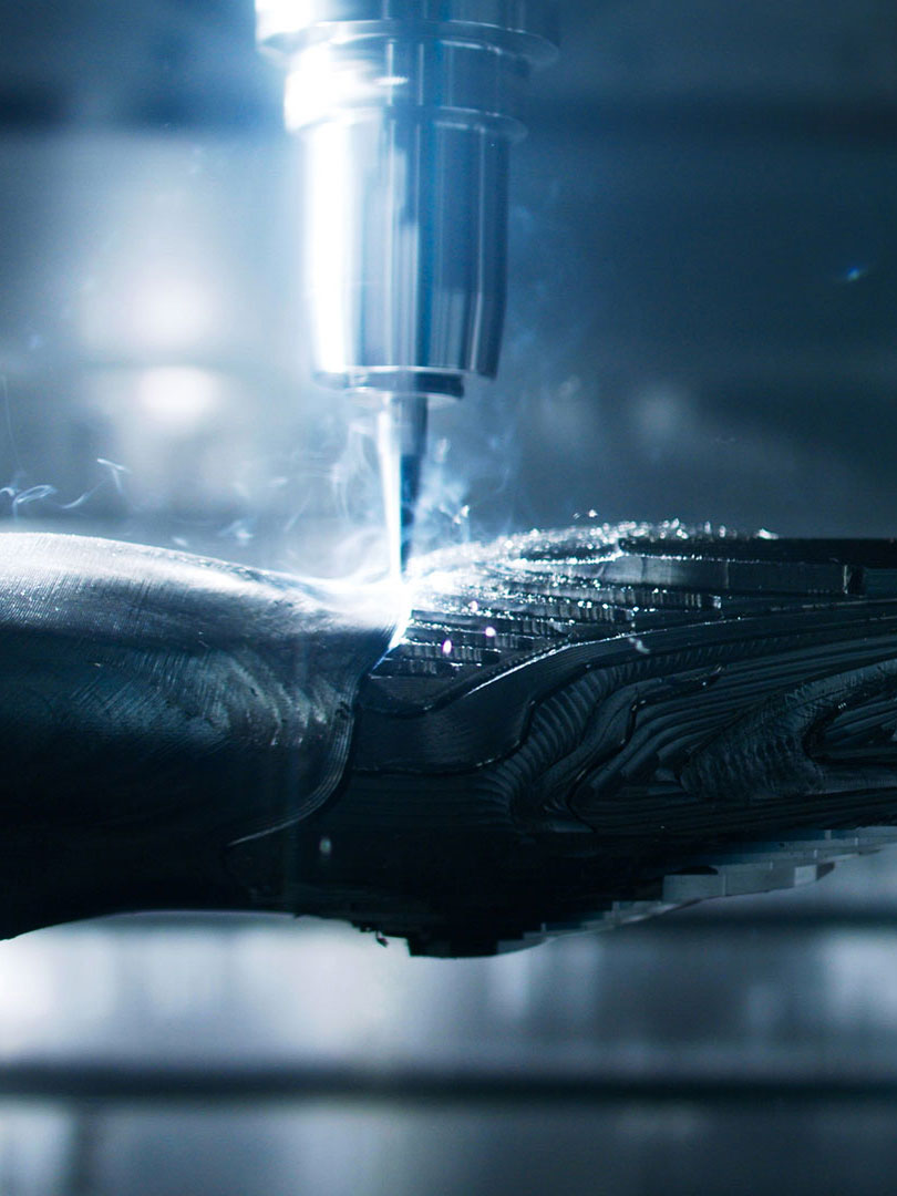 Close-up of a CNC machine cutting and shaping a metal part with sparks and smoke.