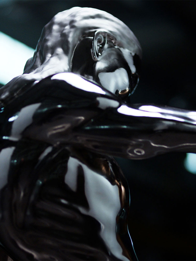 Close-up of a shiny, metallic humanoid sculpture with smooth reflective surfaces and an abstract form.