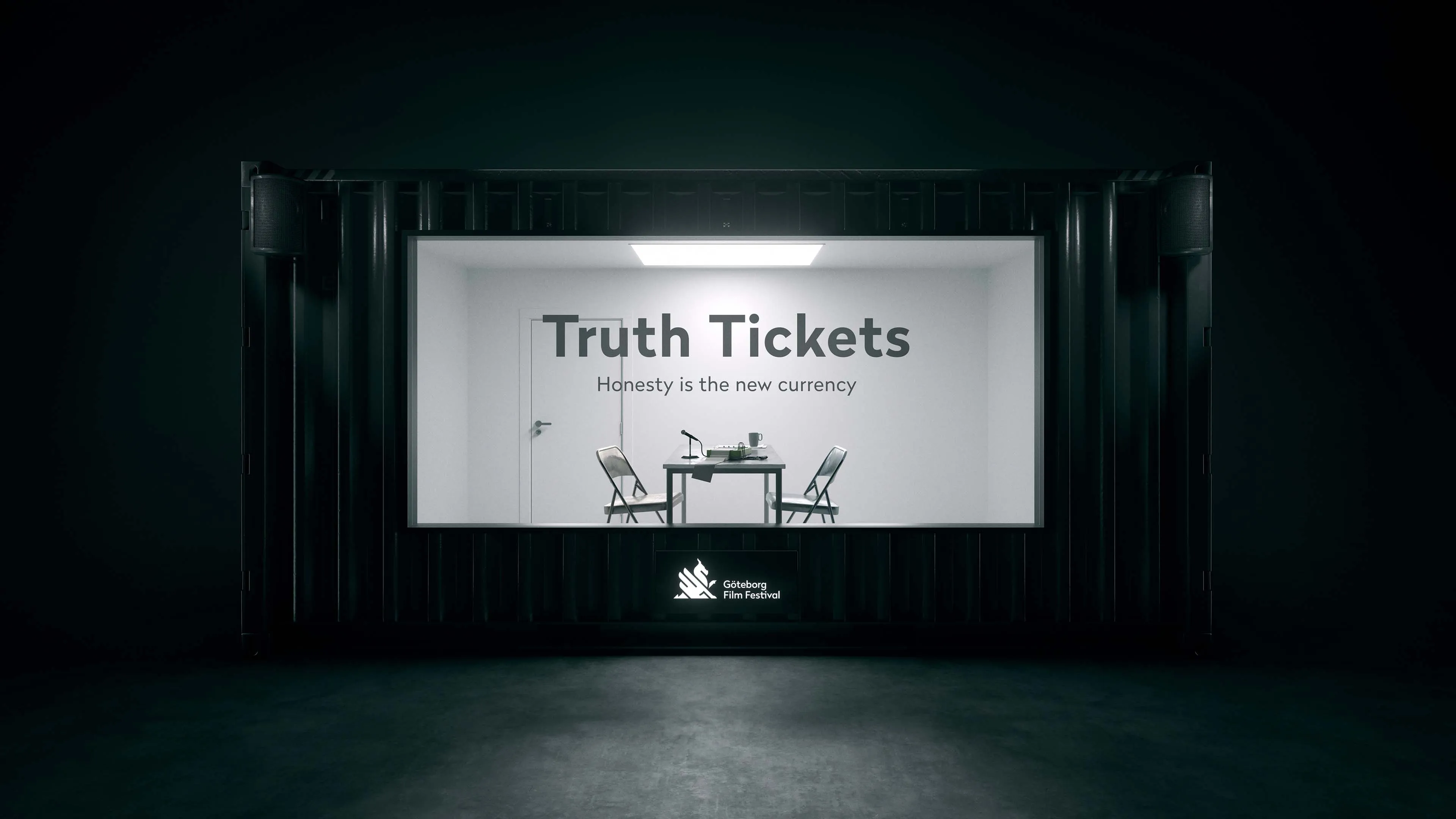 Minimalist interrogation room with two chairs and a table under a light, text on the wall says 'Truth Tickets Honesty is the new currency,' and Göteborg Film Festival logo below.