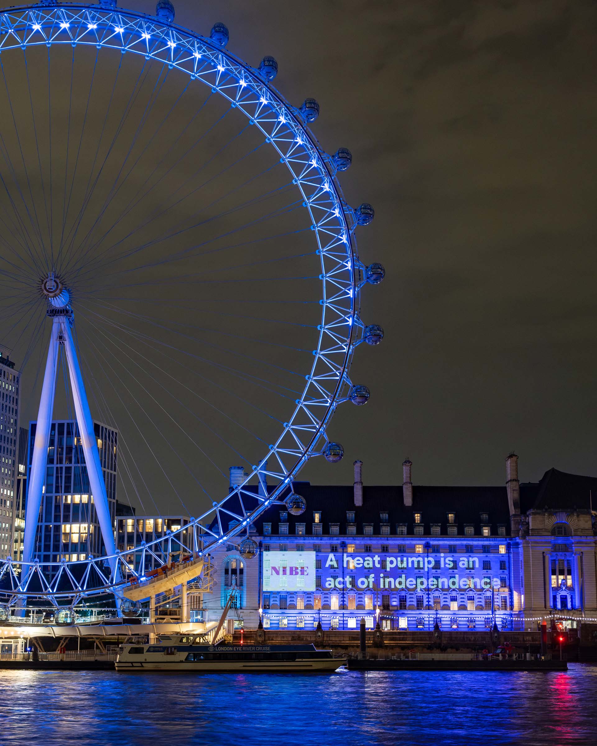 London Eye ferris wheel next to a NIBE ad projected on the side of a building.