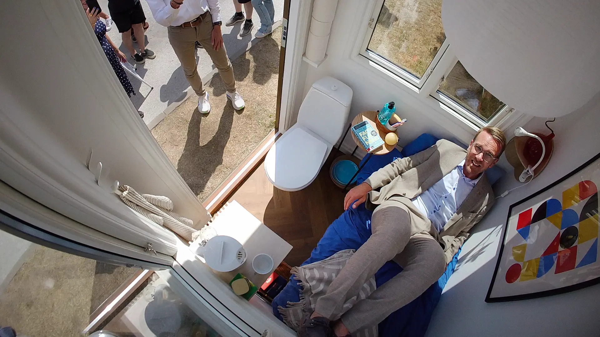 The Swedish Housing Minister squeezed in on a small bed inside a tiny room with a toilet and window.